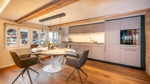 Una cocina moderna con comedor, suelo de madera y amplios ventanales.