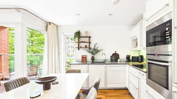 Cozinha moderna com armários brancos, uma ilha grande e eletrodomésticos de aço inoxidável.