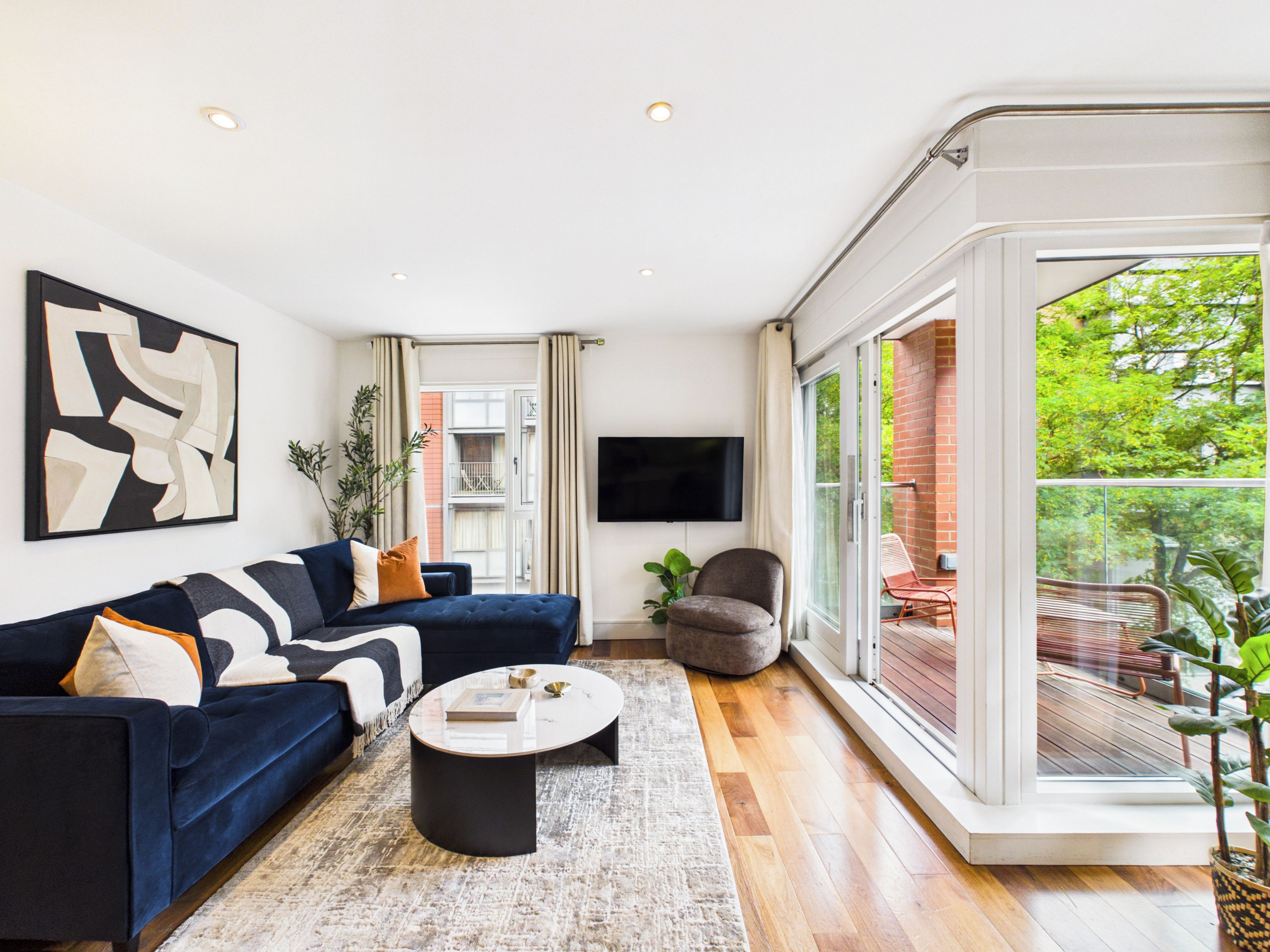A modern living room with a dark blue sofa, a round coffee table, and a large window offering a view of the outdoors.