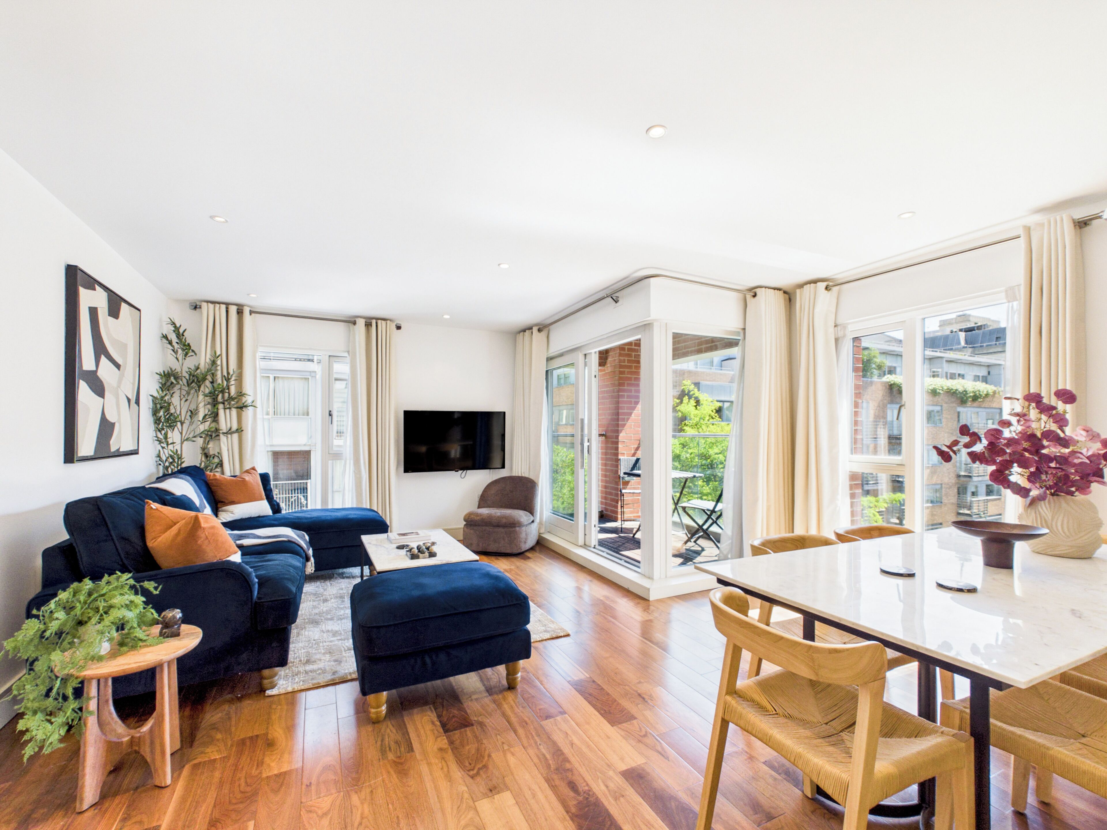 A modern living room with a sofa, ottoman, and a dining table with chairs.