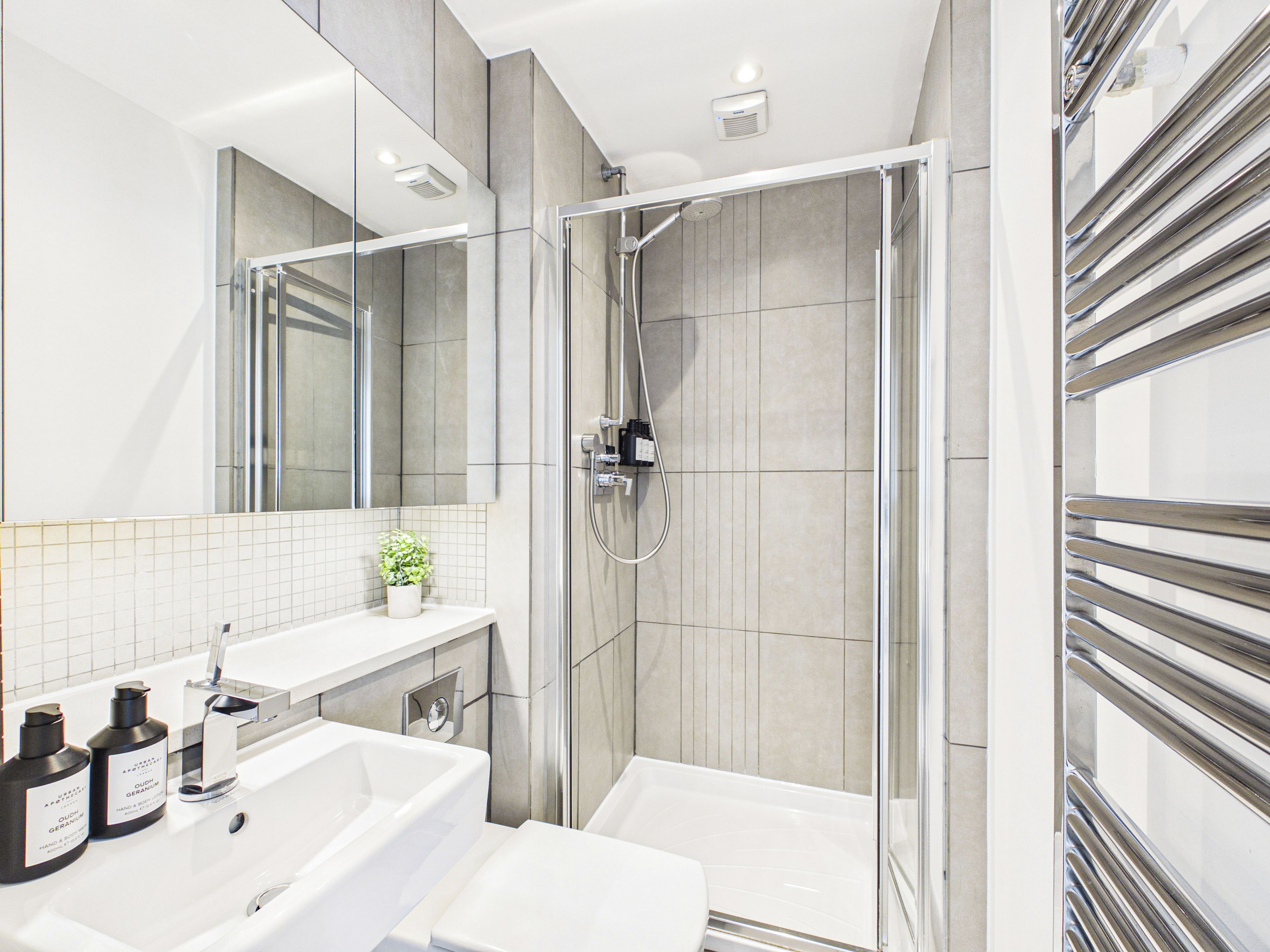 A modern bathroom with a glass-enclosed shower, a white sink, and a mirror above the sink.
