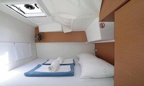 Ein kleiner, kompakter Raum mit Bett, Deckenventilator und Fenster.