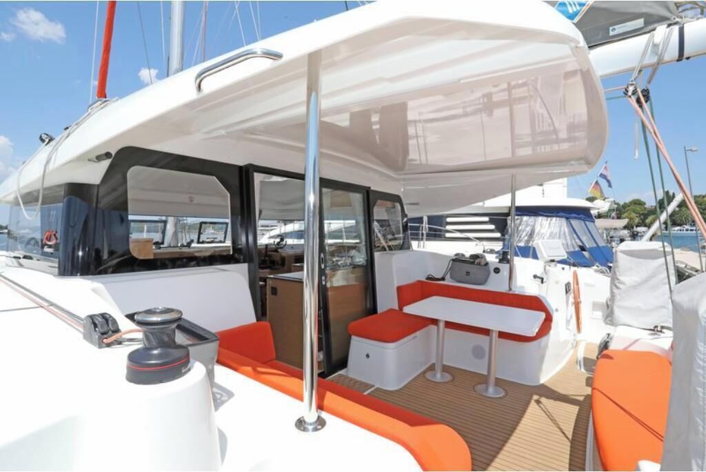 A yacht's deck with a covered seating area, a table, and a mast.