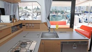 A compact kitchen with a gas stove, sink, and a view of a marina through a large window. - Excess 11 - DIOSCURI (Pula)