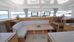 A boat interior with a dining area, a cushioned seating area, and a steering wheel. - Excess 11 - DIOSCURI (Pula)