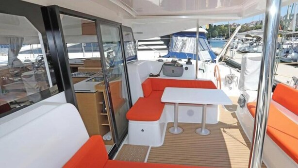 A boat interior with a seating area, a table, and a view of the marina. - Excess 11 - DIOSCURI (Pula)