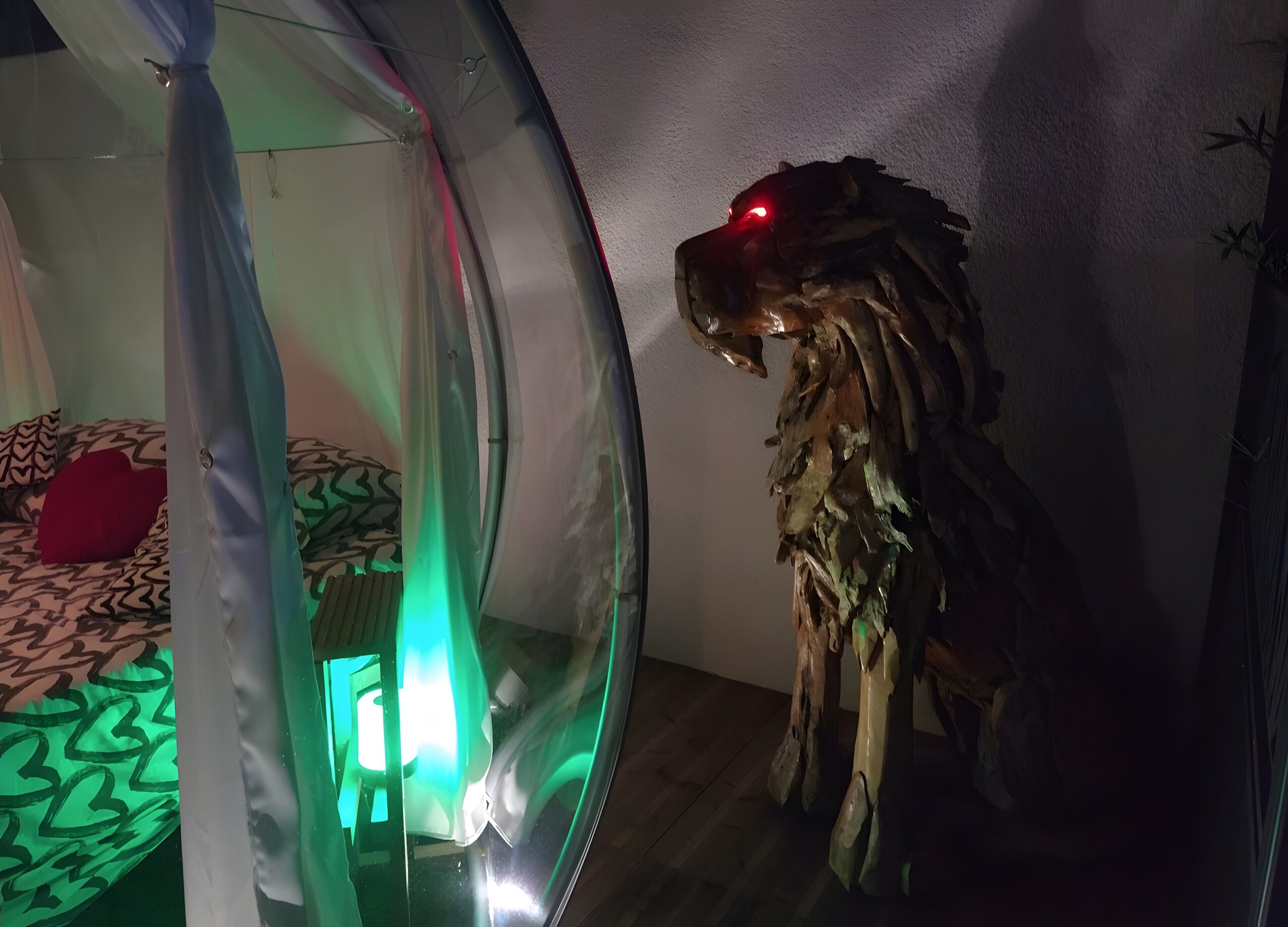 Een kamer met een rond raam, een bed met beddengoed met een patroon, en een houten sculptuur.