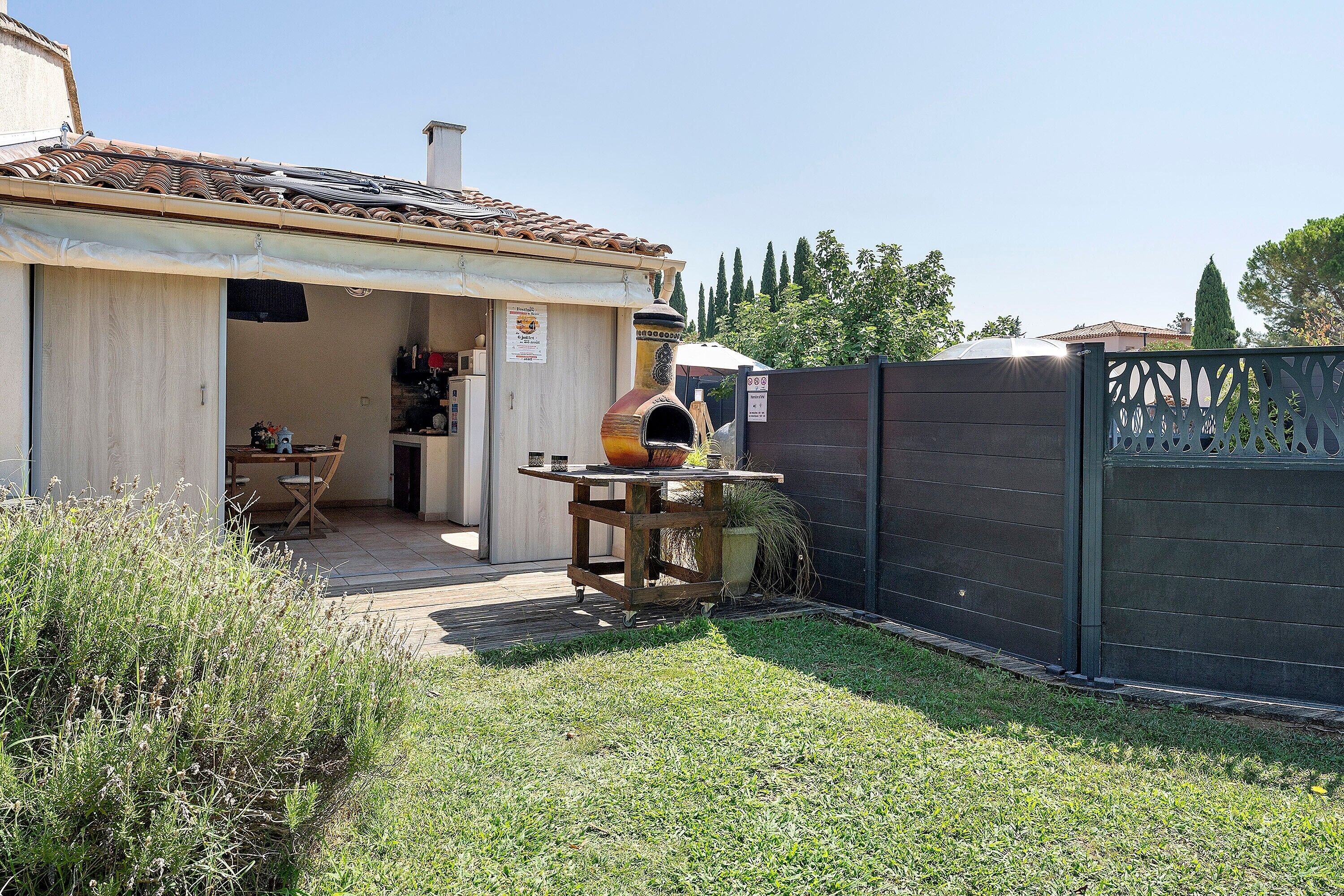 Il s’agit d’une propriété résidentielle dotée d’un patio, d’une table en bois avec un four à pizza et d’un jardin clôturé.