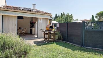 Il s’agit d’une propriété résidentielle dotée d’un patio, d’une table en bois avec un four à pizza et d’un jardin clôturé.