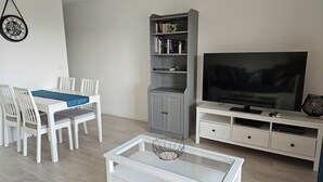 A modern living room with a dining table, chairs, a bookshelf, a television, and a coffee table. - Charming 2-room apartment - Ocean view - Pool - Parking - Antibes (Antibes)