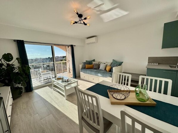 A modern apartment with a balcony, a dining area, and a kitchenette.