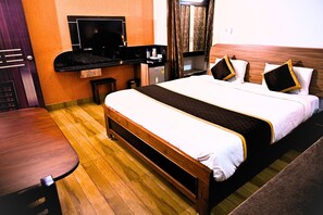 Quarto de hotel com uma cama, televisão, escrivaninha e uma cadeira.