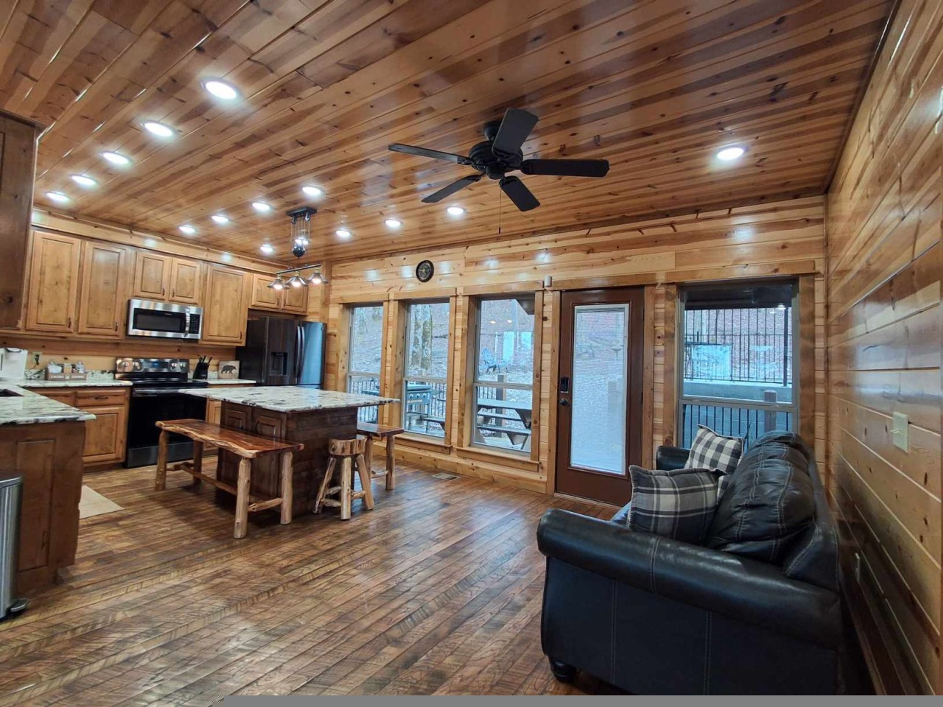 A cabin-style kitchen with wooden cabinets, a central island, and a ceiling fan.