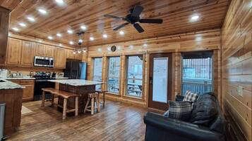 A cabin-style kitchen with wooden cabinets, a central island, and a ceiling fan.