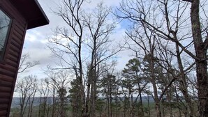 A wooden cabin with a deck overlooking a forested area. - Three Bears Pet-friendly Cabin With Heated Pool Near Hochatown Mountain Views Sleeps 10 (Broken Bow)