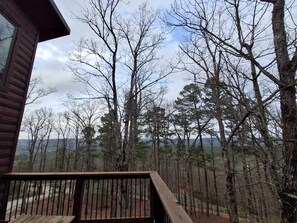 Une cabane en bois dotée d’une terrasse offrant une vue sur une zone boisée.