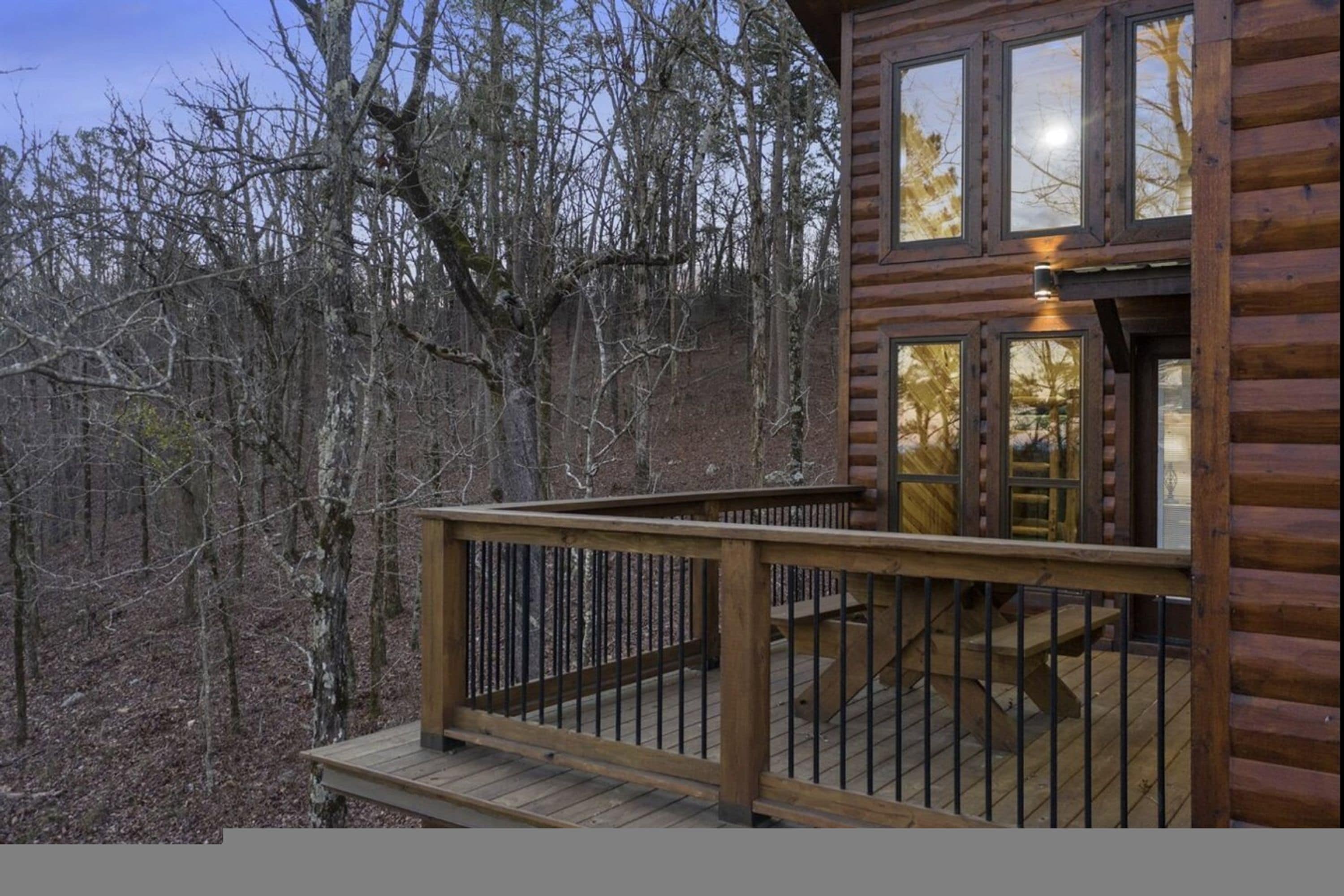 A wooden cabin with a deck and a staircase leading to a second level.