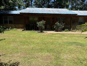 Eine Holzhütte mit einem Metalldach, einer Veranda und einem gepflegten Rasen.