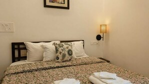 A hotel room with a bed, a wall-mounted lamp, and a framed artwork above the bed.