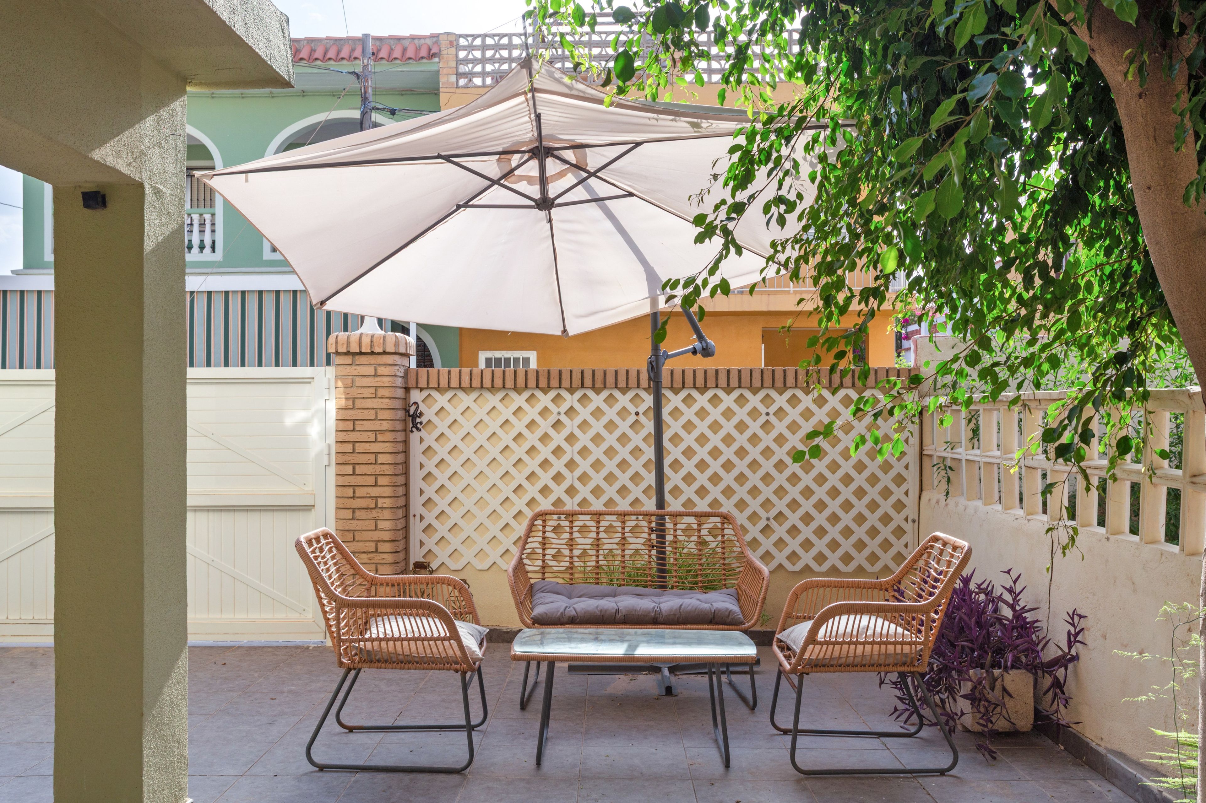An outdoor patio with wicker furniture, a table, and an umbrella.