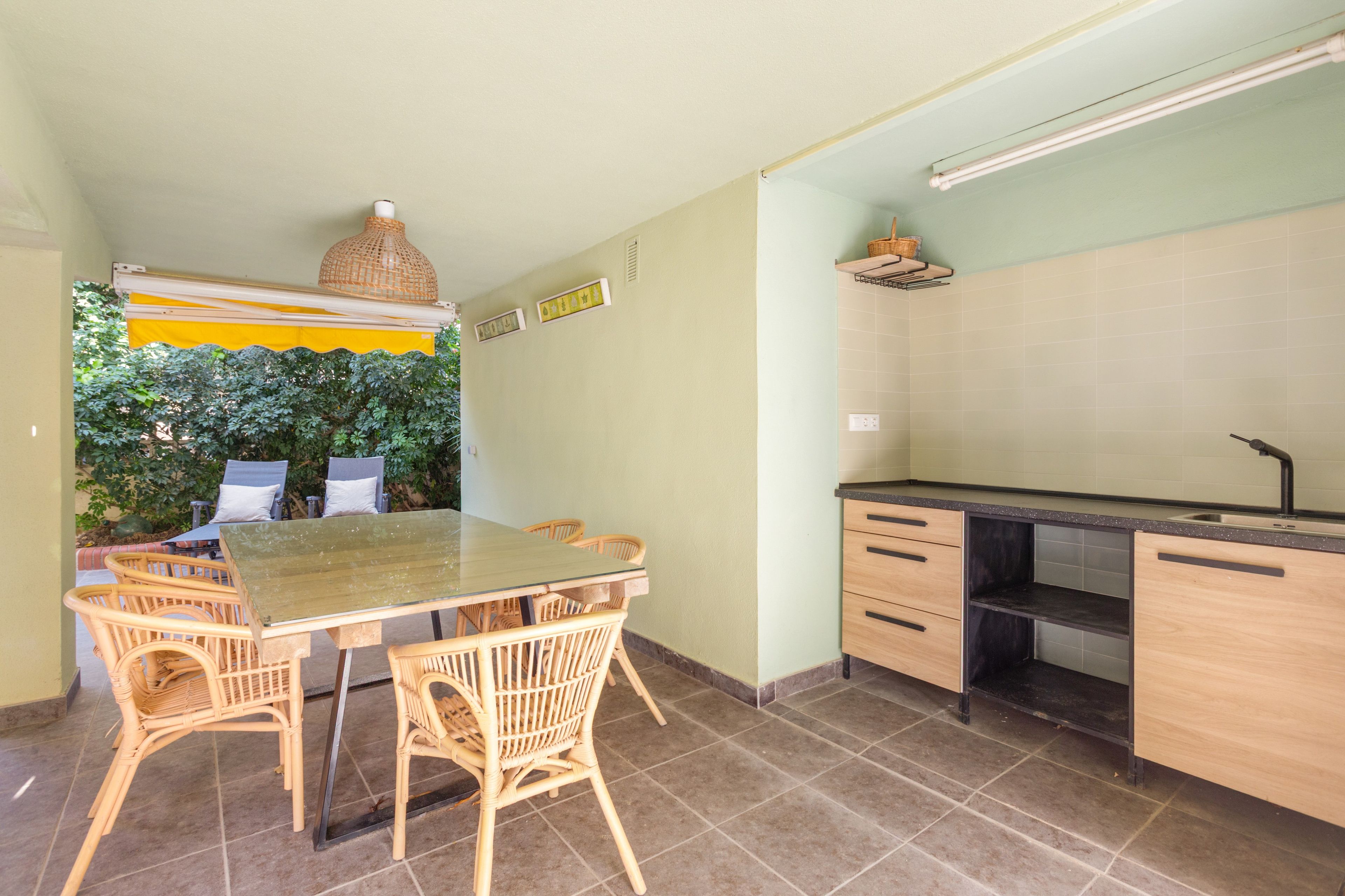 Cocina compacta con zona de comedor, que incluye una mesa, sillas, un lavamanos empotrado y una lámpara colgante.