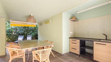 Cocina compacta con zona de comedor, que incluye una mesa, sillas, un lavamanos empotrado y una lámpara colgante.