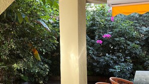 An outdoor patio area with tiled flooring, a table with chairs, and a ceiling fan.