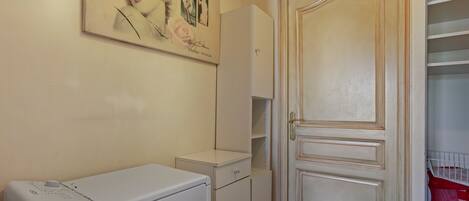 Une salle de bain équipée d’un lave-linge, d’un meuble et d’une porte avec un miroir.
