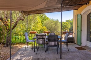 Un patio al aire libre con una mesa y sillas, rodeado por una valla de metal y follaje.