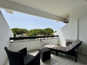 A balcony with a seating area, including a sofa and chairs, and a view of trees and buildings in the background. - Vilamoura Charming 3 With Pool by Homing (Loulé)