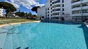 En swimmingpool ved siden af en høj bygning med altaner.