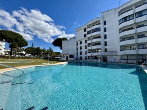 Ein Schwimmbad neben einem mehrstöckigen Gebäude mit Balkonen.