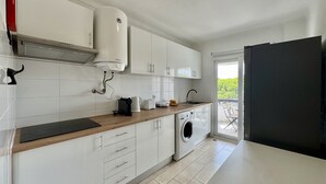 Et moderne køkken med hvide skabe, en indbygget vaskemaskine og udsigt udad.
