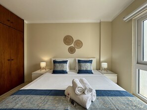 A hotel room with a large bed, two bedside tables with lamps, a wardrobe, and a view of the outdoors. - VILAMOURA CHARMING 3 WITH POOL by HOMING (Vilamoura)