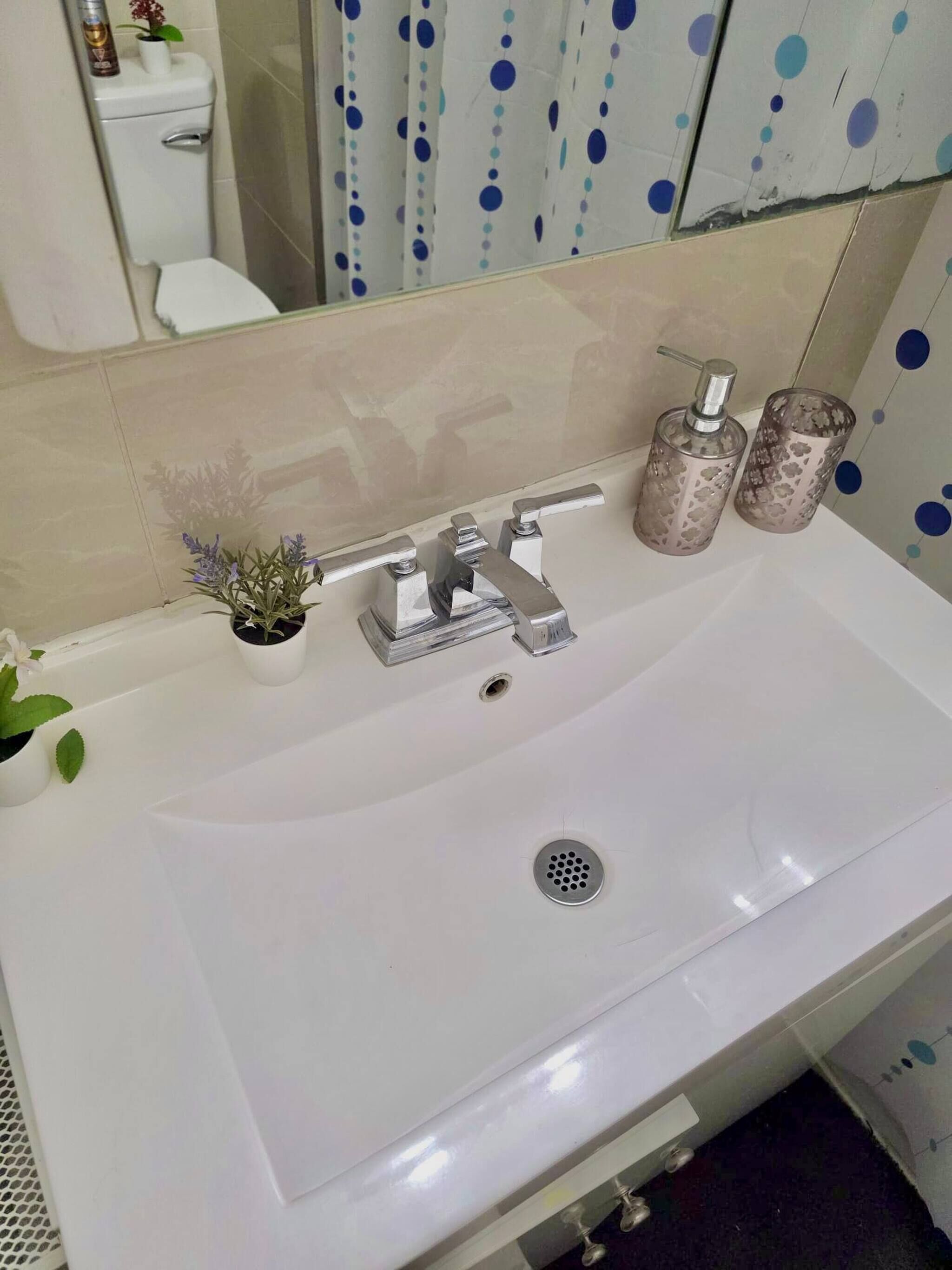 A bathroom with a white sink, a mirror, and a toilet.