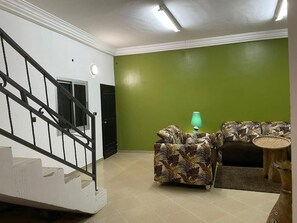 A staircase leading to a landing with a green wall and a patterned sofa.