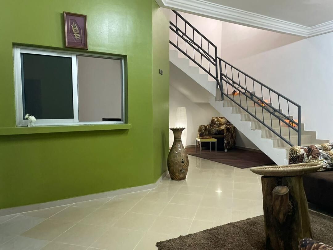 A living room with a staircase, a vase, and a sofa.