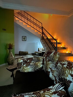 A living room with a staircase, a sofa, a table, and a vase.