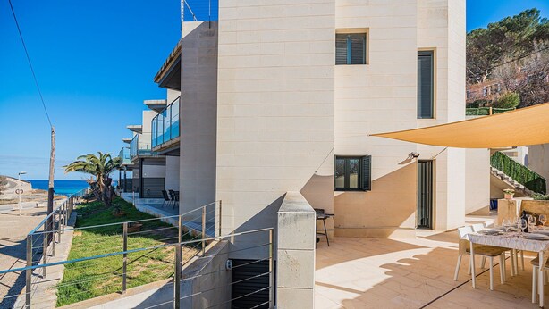 Un bâtiment moderne doté d’un patio, d’un espace extérieur aménagé pour s’asseoir et offrant une vue sur la mer.