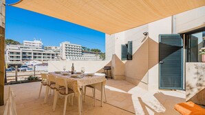 Une terrasse extérieure avec une table dressée pour le repas, une chaise et un parasol.