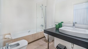 Une salle de bain moderne avec une douche à parois de verre, des toilettes blanches, un plan de toilette noir et un cactus vert en guise de décoration.
