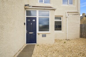 A house with a dark blue door, a small window, and a nameplate on the wall. - Kilrenny - North East Escapes (Seahouses)