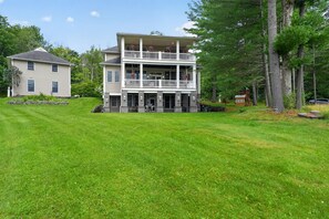 A two-story building with a balcony, surrounded by a well-maintained lawn and trees. - Oquaga Lakefront | Dock, Kayaks & Sunsets (Deposit)