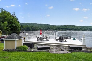 A lakeside deck with outdoor furniture and a small shed. - Lakefront Catskills Retreat | Dock & Sunsets (Deposit)