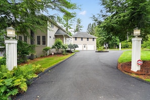 A residential driveway leading to a house with a garage, surrounded by lush greenery and a well-maintained lawn. - Oquaga Lakefront | Dock, Kayaks & Sunsets (Deposit)