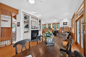 A spacious living room with a fireplace, wooden flooring, and a dining area with a long table. - Oquaga Lakefront | Dock, Kayaks & Sunsets (Deposit)