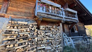 A wooden cabin with a balcony and a stack of firewood against the wall. - Pink Room in a Wooden Chalet (Demi-Quartier)