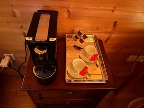 Une table en bois, avec une machine à café et un plateau contenant des tasses et des soucoupes.