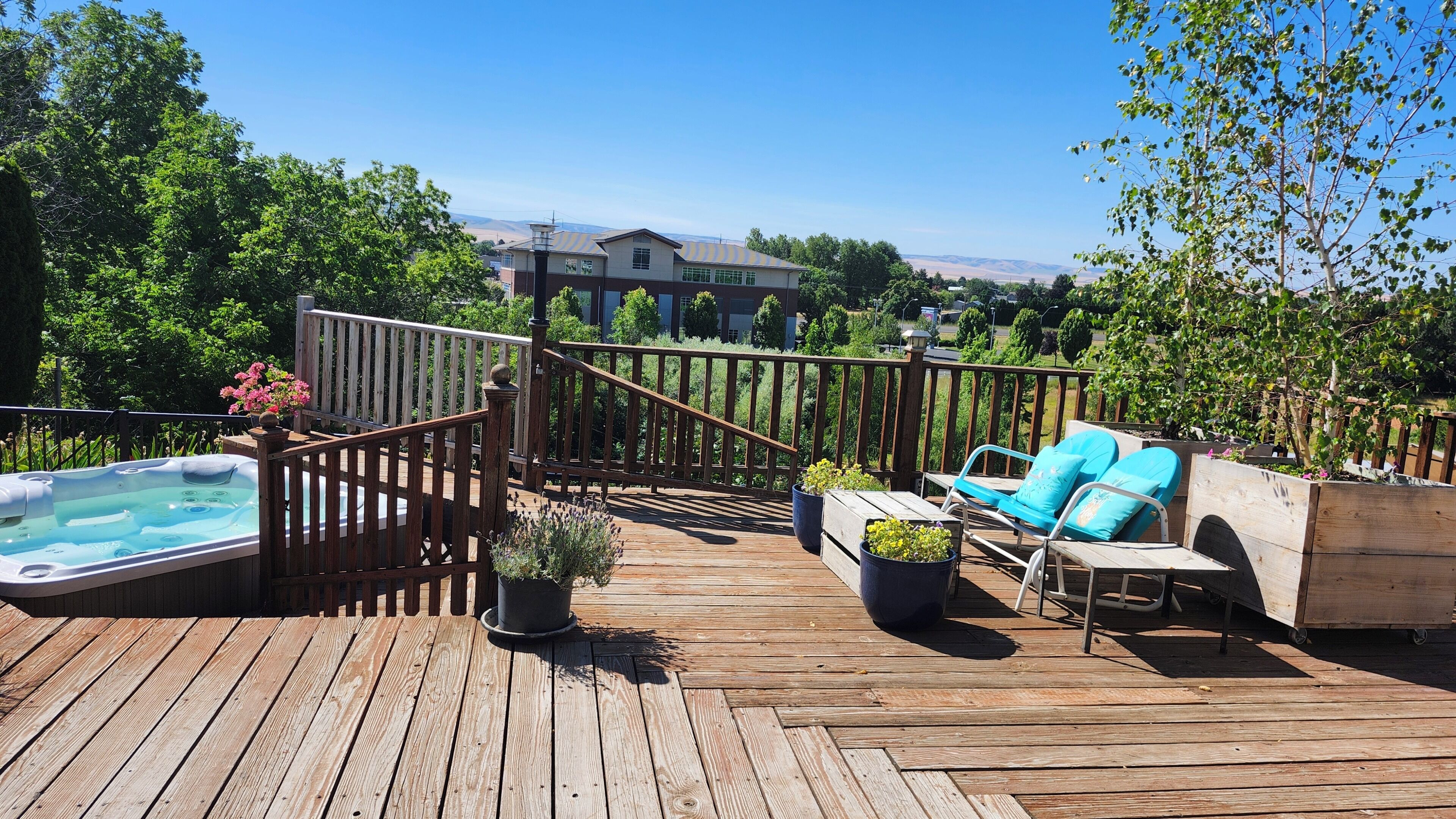 Une terrasse en bois avec un jacuzzi, des chaises longues et des jardinières.