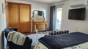 Een slaapkamer met een bed, een dressoir, een spiegel, een kledingkast en een televisie.